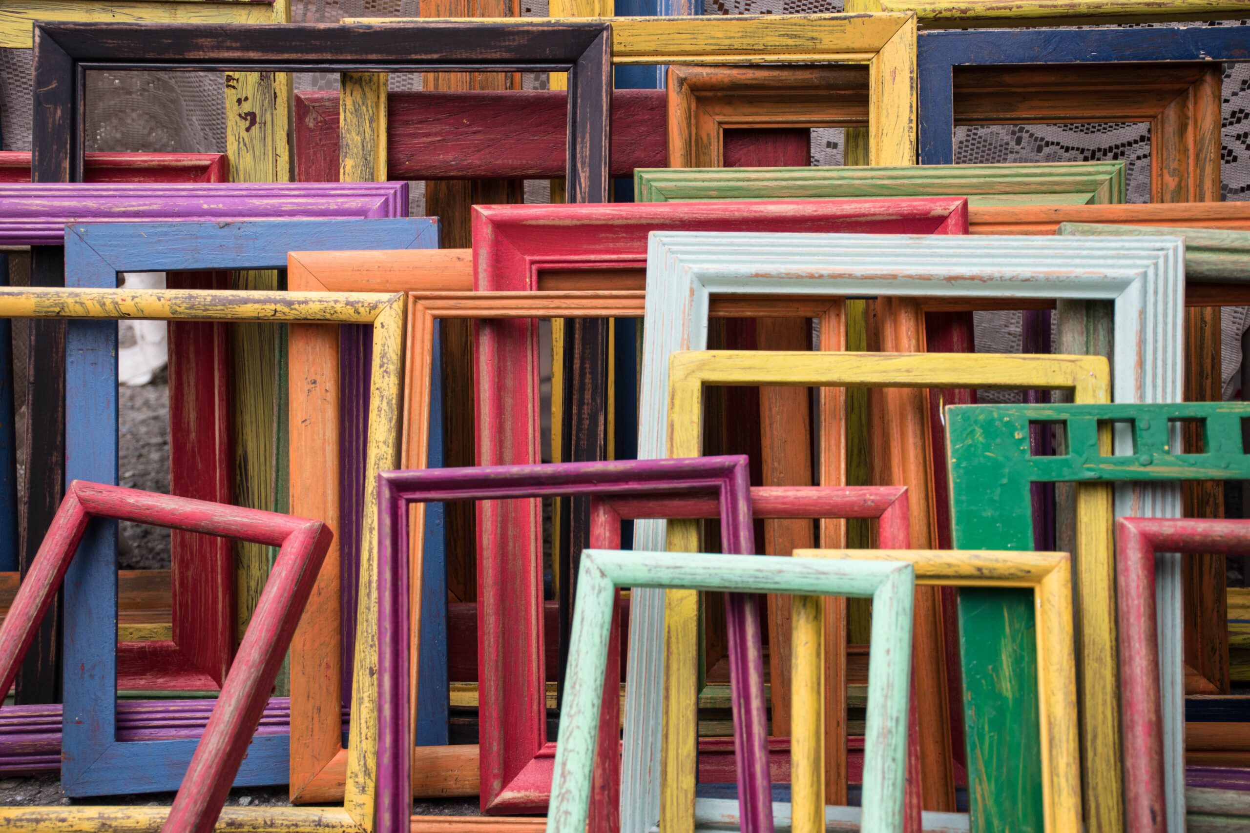 Empty picture frames of various size and colour stacked atop one another